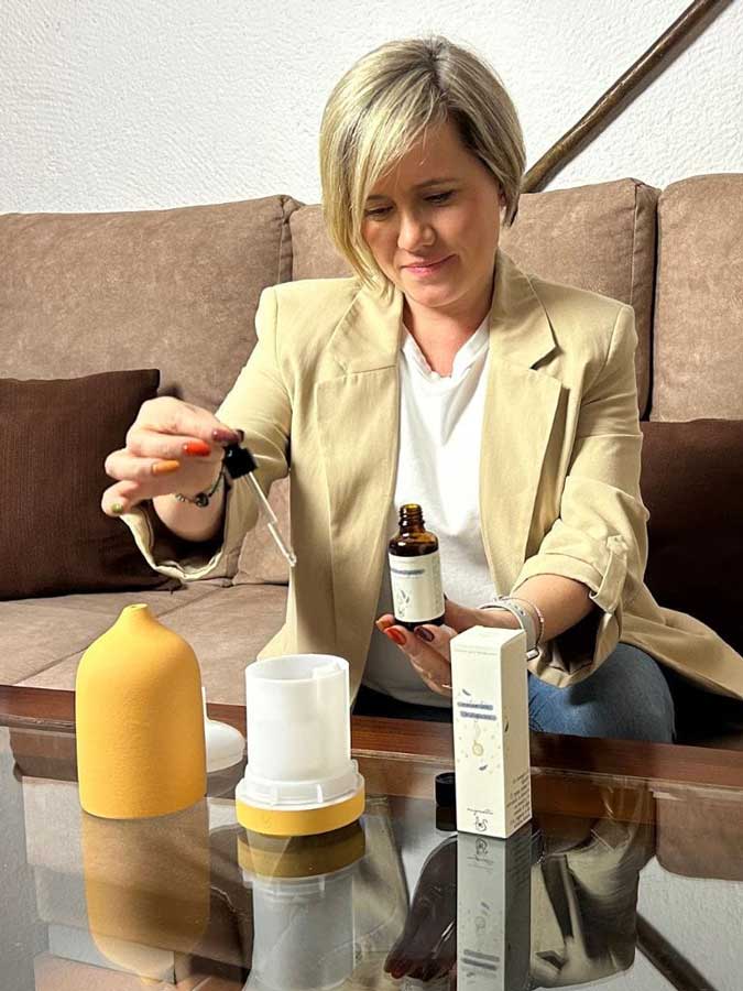 Ana Belén preparando el difusor Tempo, con una pipeta pone la esencia, en un salón acogedor.