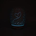 Difusor de perfume estela encendido. Los puntitos en forma de corazón están iluminados con luz azul.