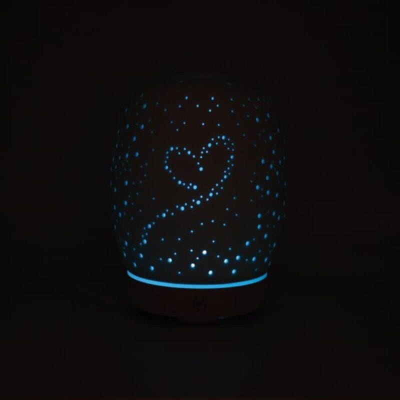 Difusor de perfume estela encendido. Los puntitos en forma de corazón están iluminados con luz azul.