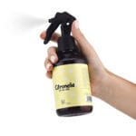 Spray para textil de citronela antimosquitos en la mano de una mujer pulverizando. Contiene 250ml.